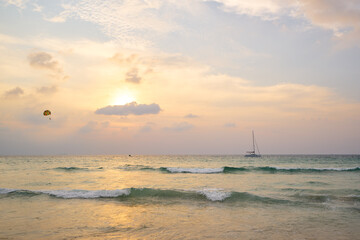 Serene Ocean Sunset With Gentle Waves and Sailboat in the Distance