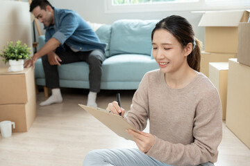 Move house, relocation. Woman using household checklist for new apartment Inside the room are...