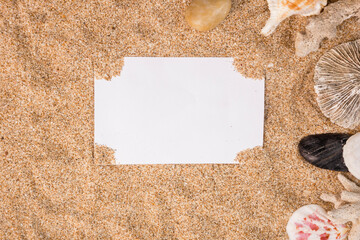 blank white paper with shells on the sand