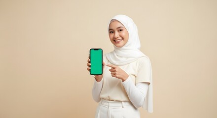 Young Woman Wearing White Hijab Holding Smartphone Showing Green Screen in Studio