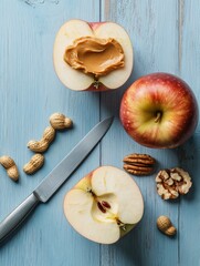 A knife is on a table with a sliced apple and a nut