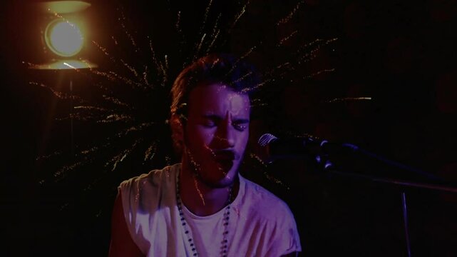 Drummer intensifying strikes drum kit under spotlight activating fireworks behind head for climax