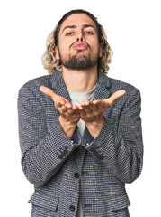 Young businessman in casual blazer folding lips and holding palms to send air kiss.