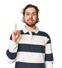 Young Caucasian man in studio setting showing number one with finger.