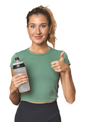Blonde athlete with water bottle smiling and raising thumb up