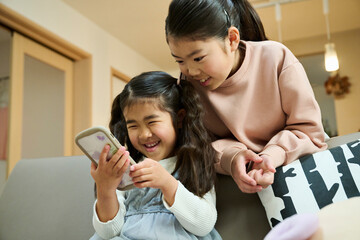 姉妹がスマートフォンで遊ぶ微笑み