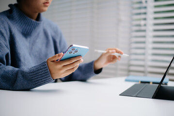  Woman hand using a blue smartphone in a modern office, focusing on mobile communication, digital work, and productivity.