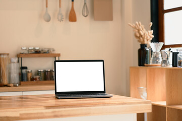 Laptop with blank screen on a wooden kitchen counter.