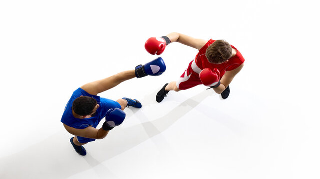 Two athletes are sparring in a boxing ring, one in blue gear and the other in red, viewed from an aerial perspective. Concept of competitive sportsmanship and training.