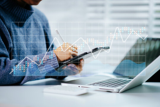 Real person using a stylus on tablet with digital trend graph overlay and laptop. Ideal for fintech, analytics, report, chart,