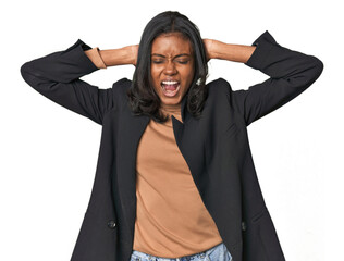 Young Indian woman in business suit covering ears with hands trying not to hear too loud sound.