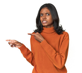 Portrait of a young Indian woman shocked pointing with index fingers to a copy space.