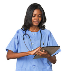Young Indian nurse reading from a tablet in a studio setting