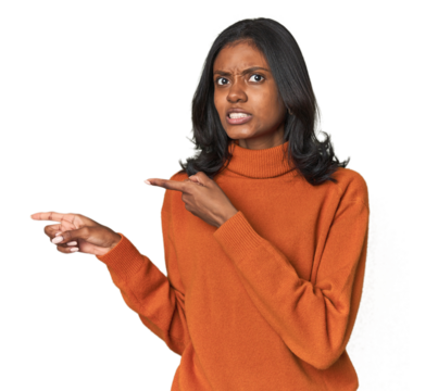 Portrait of a young Indian woman shocked pointing with index fingers to a copy space.