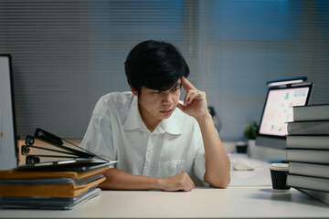 Overworked employee thinking hard in a modern office at night
