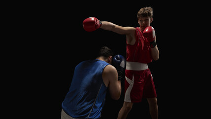 A boxer in red delivers a powerful punch to a blue-clad opponent during an intense match set...