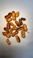 Scattered peanuts in their shells present a natural snack against a plain white background, food photography