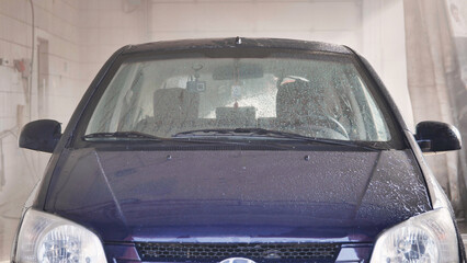Car going through automatic car wash getting soaped and rinsed