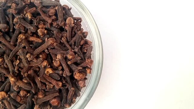 Half of circle shaped Cloves glass bowl in the left half of the frame, rotating, isolated on the white background, closeup, herbs and spices