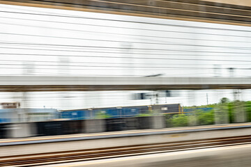 Dynamic motion blur view from high-speed train window: Green landscape, trees & fields rush past at high speed