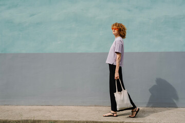 Woman walking confidently in lavender shirt and tote bag