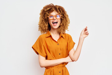 Smiling girl with curly hair in orange outfit against neutral background showcasing joy and...