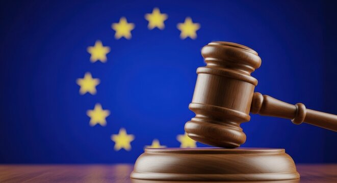 European Union regulations and judgment. A close-up of a judge's gavel on its sound block with the flag of the EU blurred in the background.