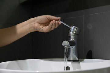 close up Woman open pull chrome faucet washbasin to washing hand soap for corona virus at water...
