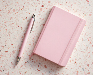 Stylus pen and closed notebook on terrazzo background, pastel pink color palette, modern minimalism, top-down view