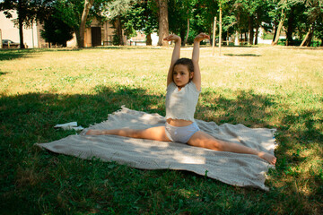 Young girl in a park, practicing splits on a blanket, radiating focus and determination. Ideal for...