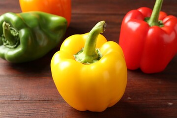Ripe colorful bell peppers on wooden table, closeup