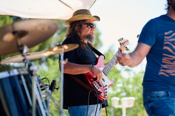 Rock band performing outdoors with guitarist in stylish hat and sunglasses