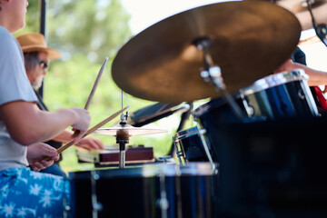 Rock band performing live outdoors with drummer and musicians on stage
