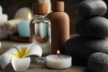 Composition with cosmetic products and spa stones on wooden table, closeup