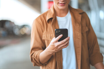 Close-up portrait of happy asian man smiling while booking flight tickets on airline website using...