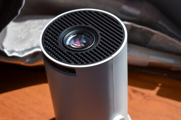 modern white portable projector standing on a soft fabric surface in natural light. concept of home...