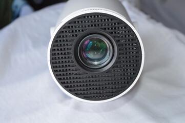 modern white portable projector standing on a soft fabric surface in natural light. concept of home...