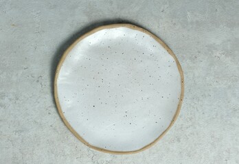 A white ceramic plate, pottery plate on gray background. Textured, handmade, empty plate concept....