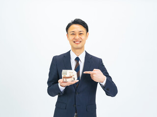 住宅模型を持って案内するミドルエイジ男性ビジネスパーソン