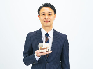住宅模型を持つミドルエイジ男性ビジネスパーソン