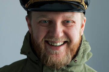 Bearded and cheerful man in a naval captain's cap.