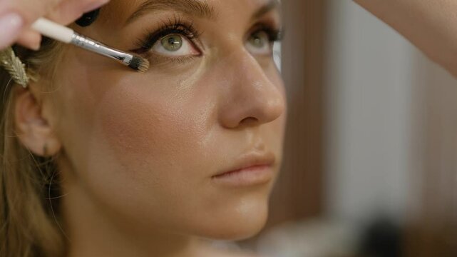 Under eye circle corrector, foundation. Makeup artist applies under eye circle corrector cream to model face. Close-up