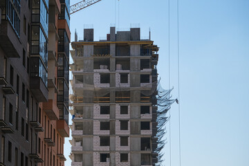 A large building is under construction with scaffolding and a crane