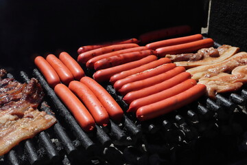 Sausages and Bacon on a hot black BBQ