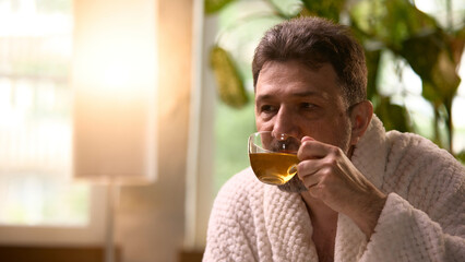 Lifestyle and wellness. Caucasian man in a robe enjoys tea in a peaceful morning setting. Concept...