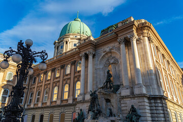 Majestic view of Buda Castle’s ornate facade and Matthias Fountain under golden sunlight in...