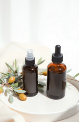 Two mockup skincare bottles &mdash; one spray and one dropper &mdash; on matte ceramic tray, surrounded by olive branches and soft beige linen, light shadows, neutral background