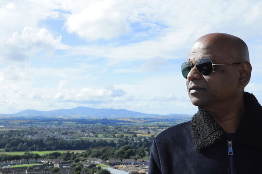 Confident Man Overlooking Enniscorthy Town from Vinegar Hill Summit, County Wexford, Ireland on a Bright Sunny Evening &ndash; Panoramic Hilltop View with Lush Green Fields and Rolling Hills