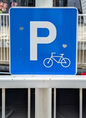 Close-up photo of a Blue Bicycle Parking Sign with a small carved  hearts on a metal pole