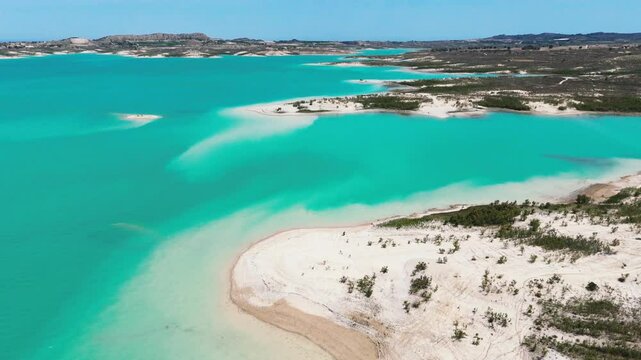 Aerial view of Embalse de La Pedrera reservoir landscape, with striking turquoise waters, curving white-sand shores, and desert-like hills. Costa Blanca. Province of Alicante. Spain	